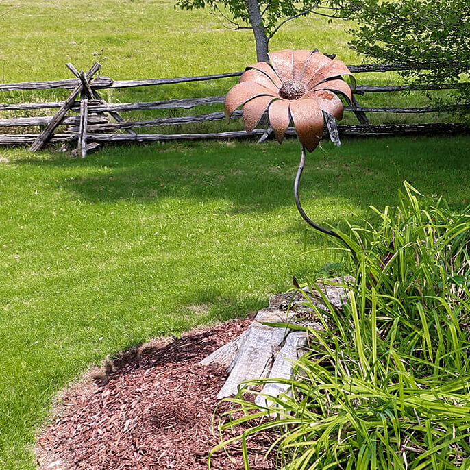 split-rail fence and metal flower sculpture in a yard
