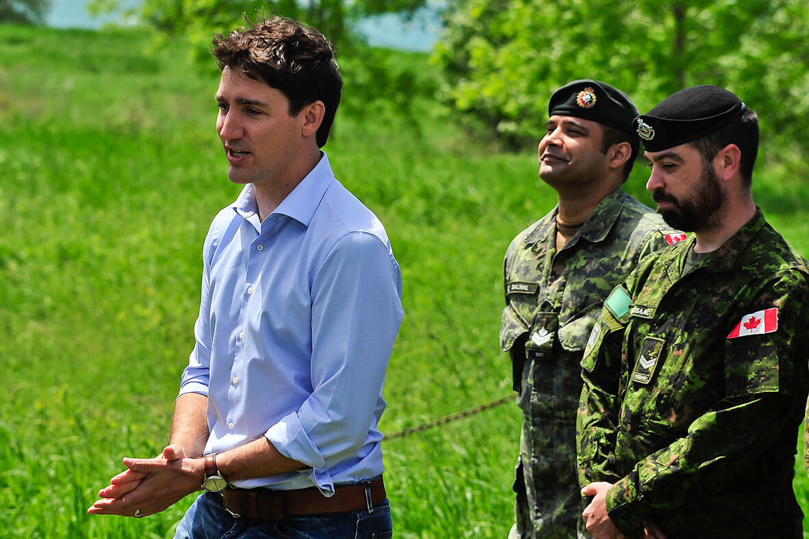 prime minister speaking with two uniformed soldiers behind him