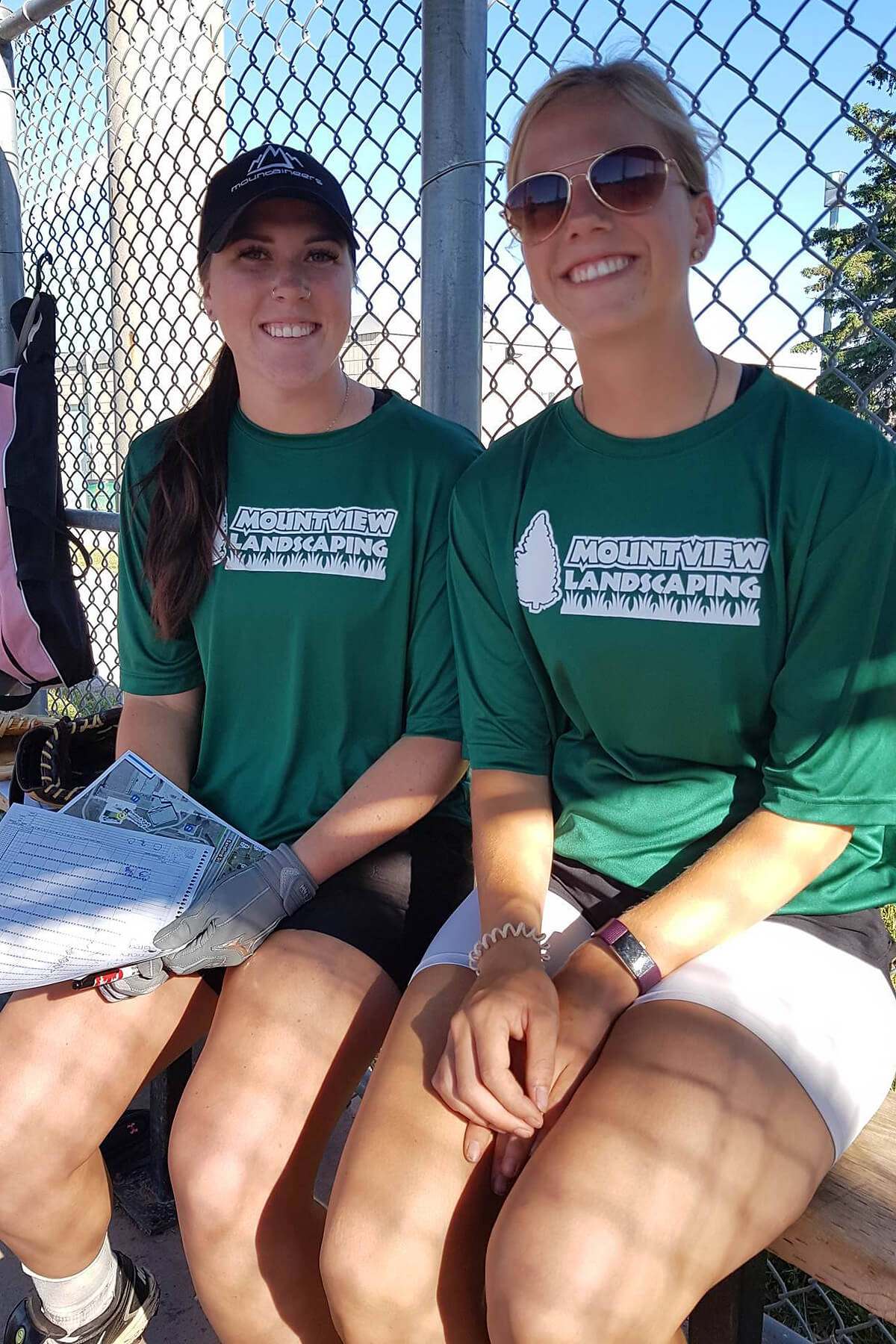Two happy girls sitting on baseball dugout bench