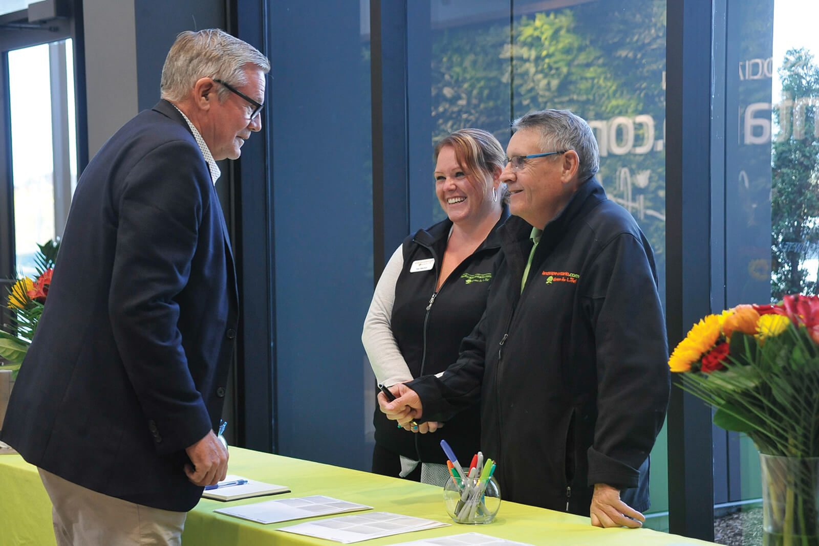 man talking with man and woman at a registration table