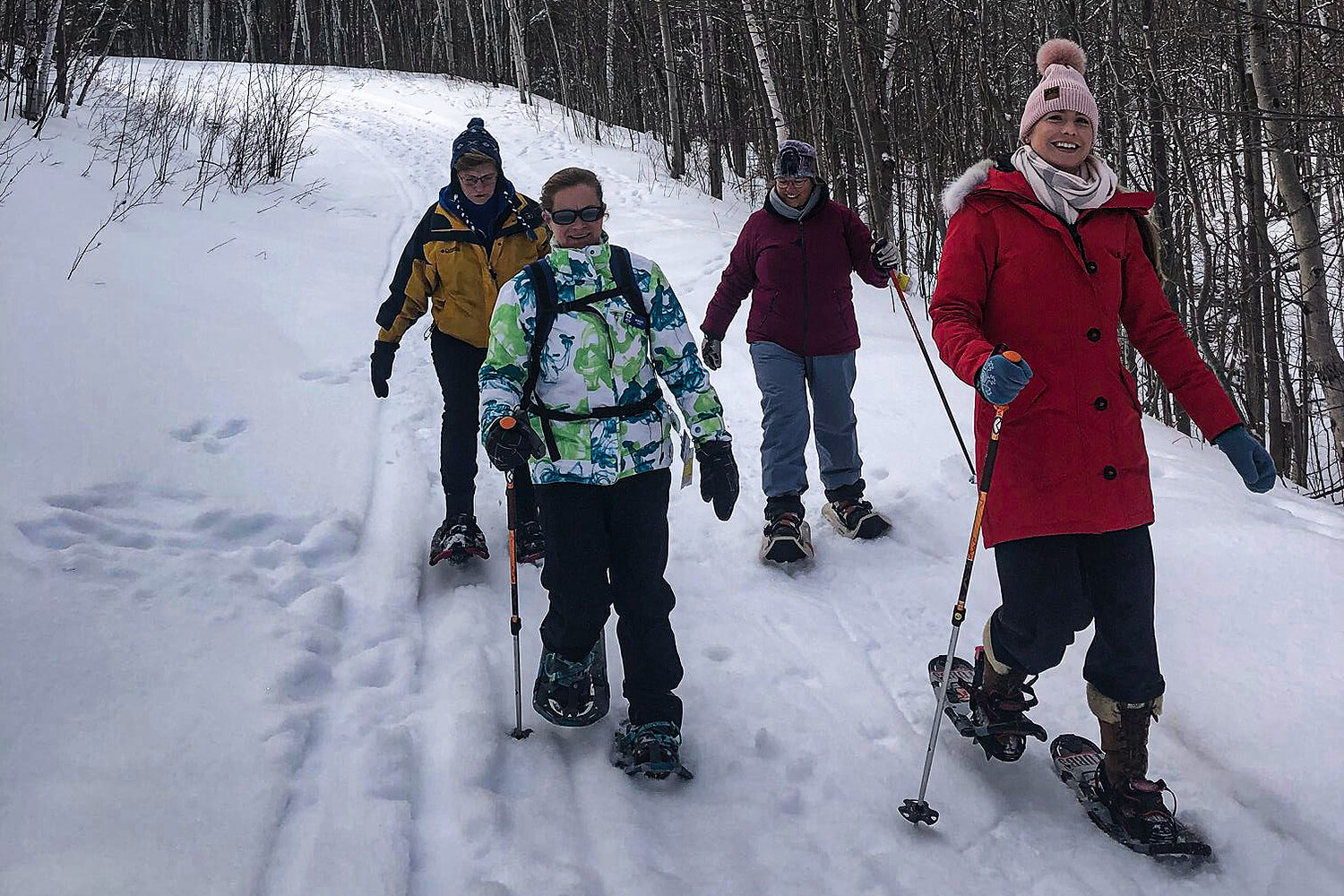 four women snowshoeing on a trail
