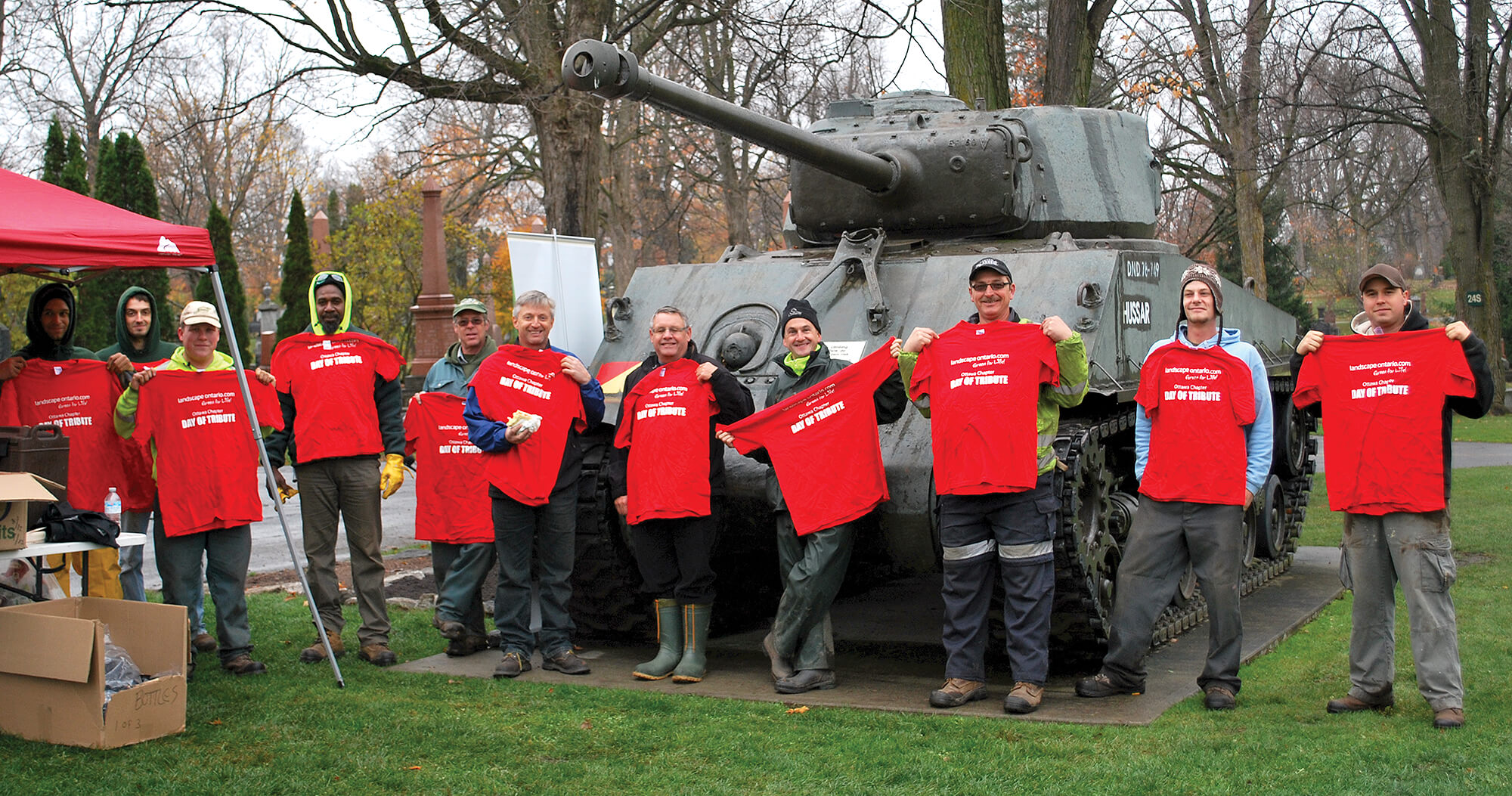 group of volunteers in front of a tank at military cemetary