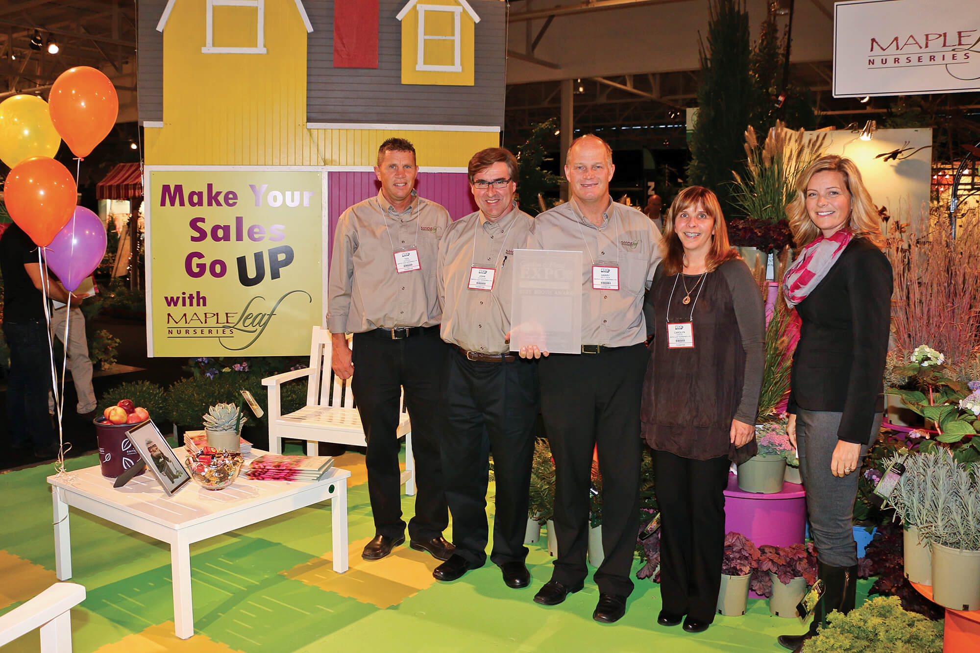 five people standing in a colourful trade show booth