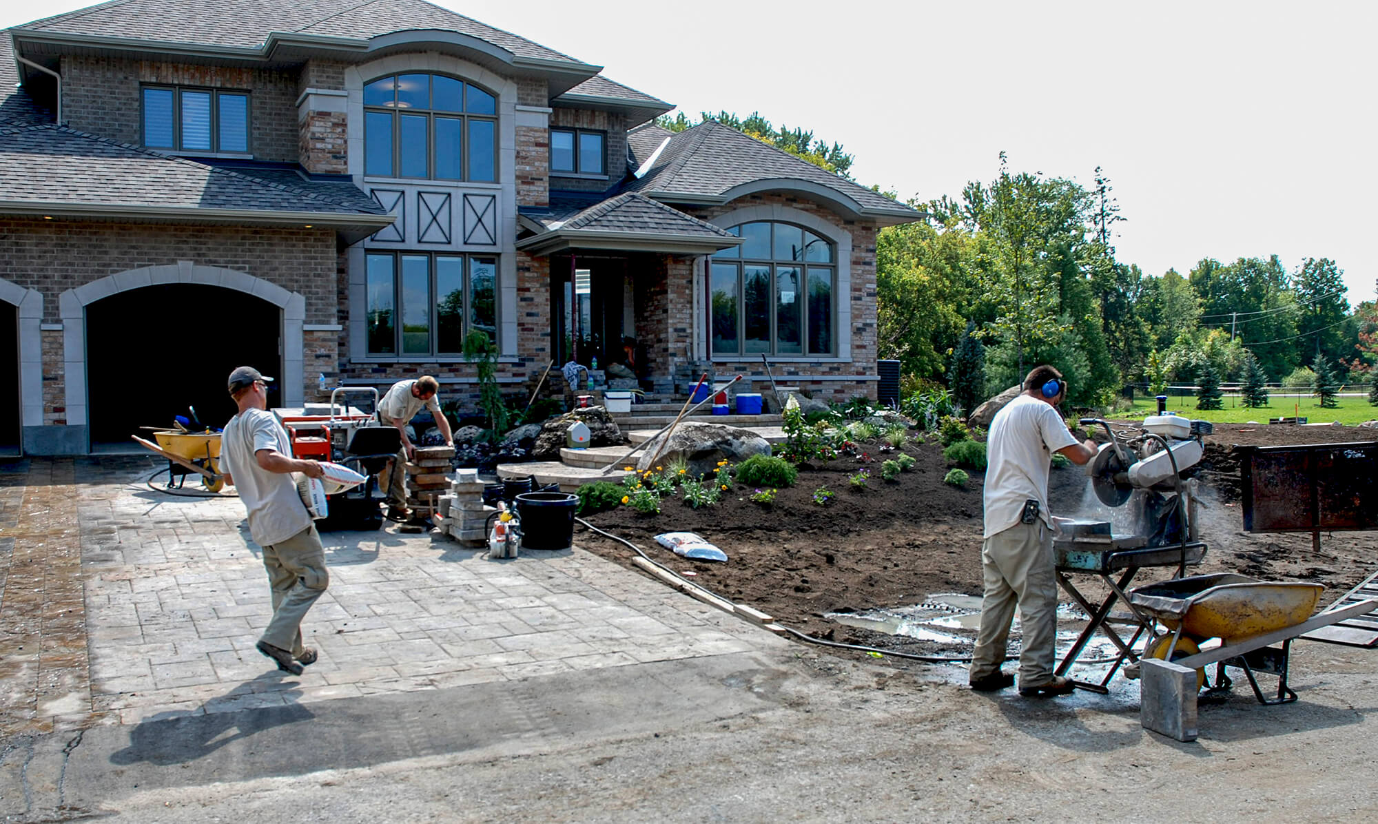 men working on the landscape in the front yard of a home