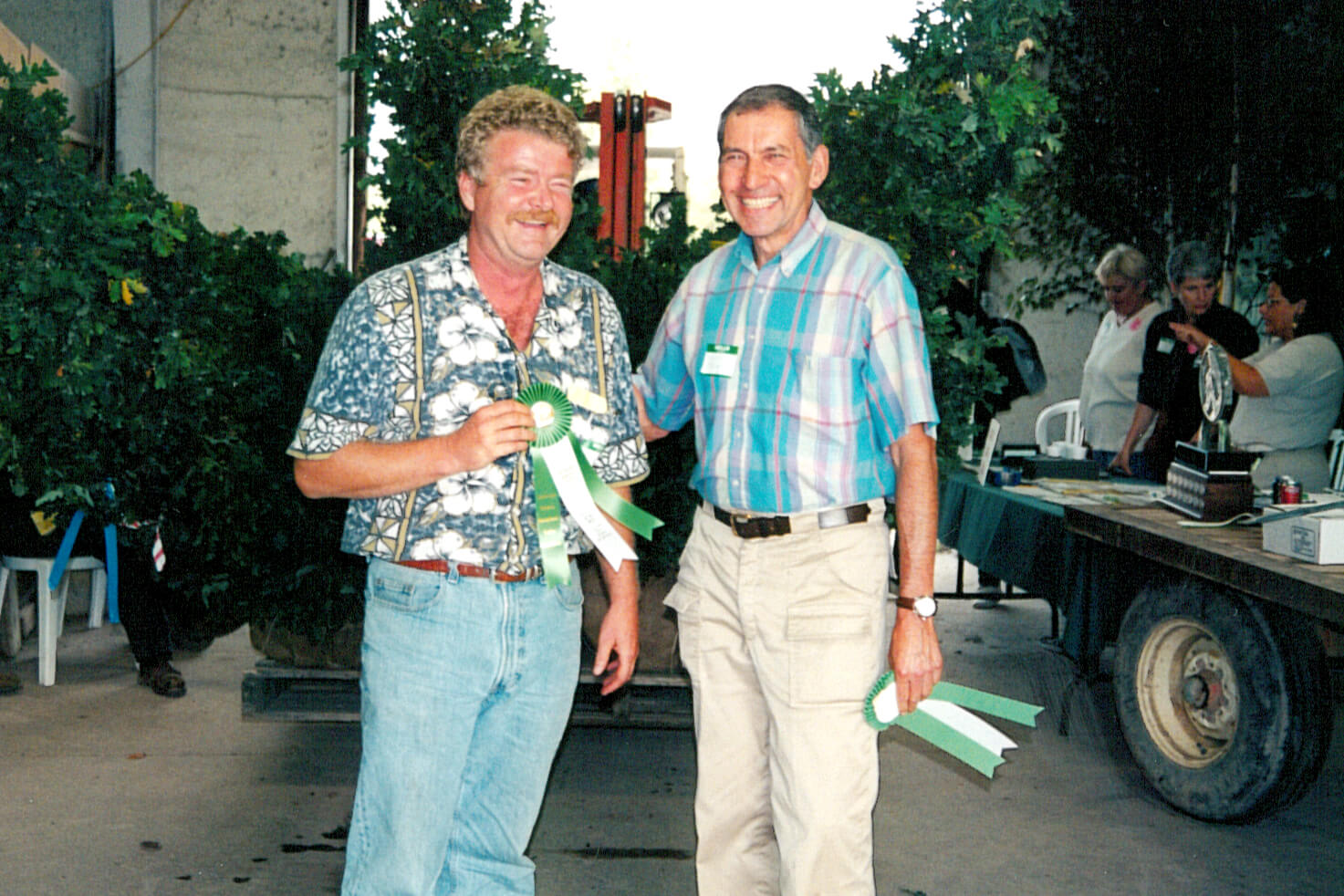two men, one holding a prize ribbon