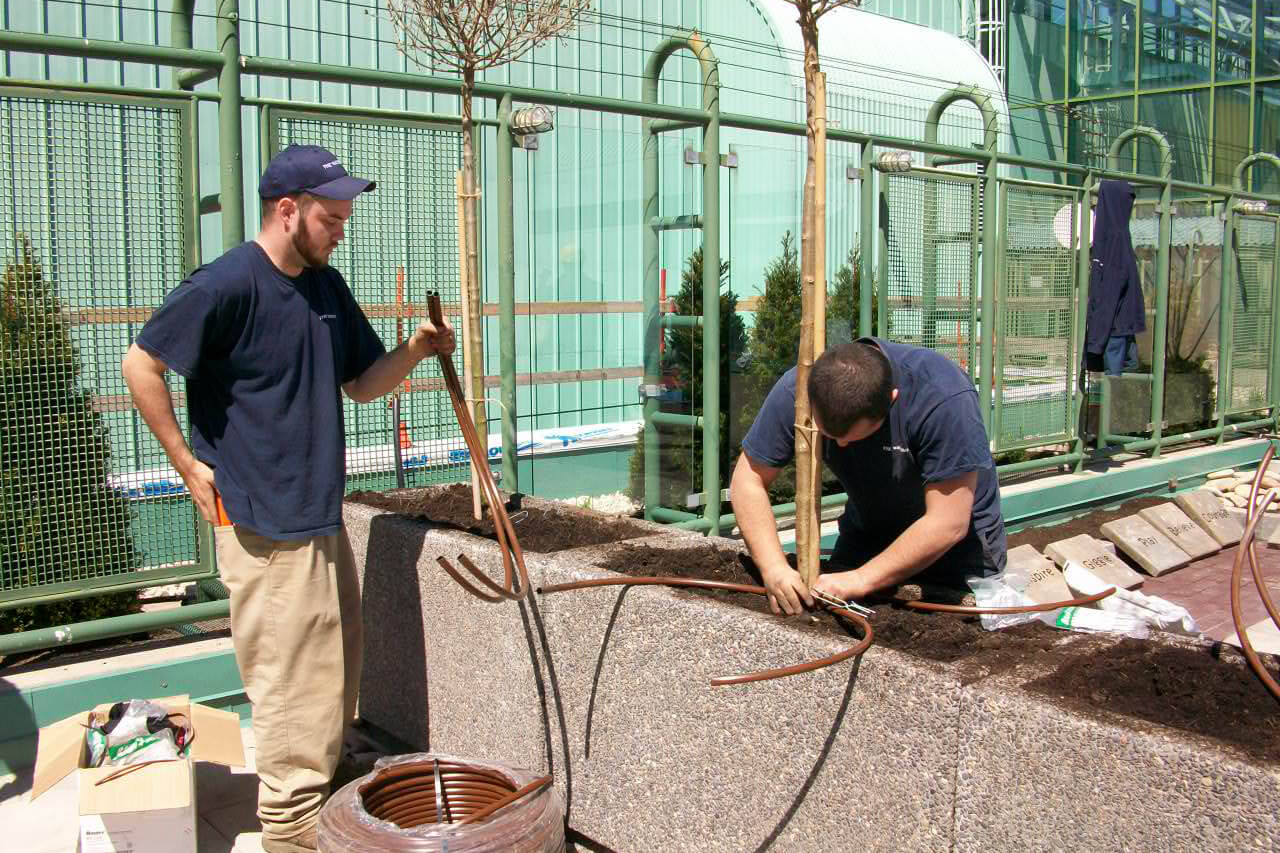 two men installing irrigation in a planter