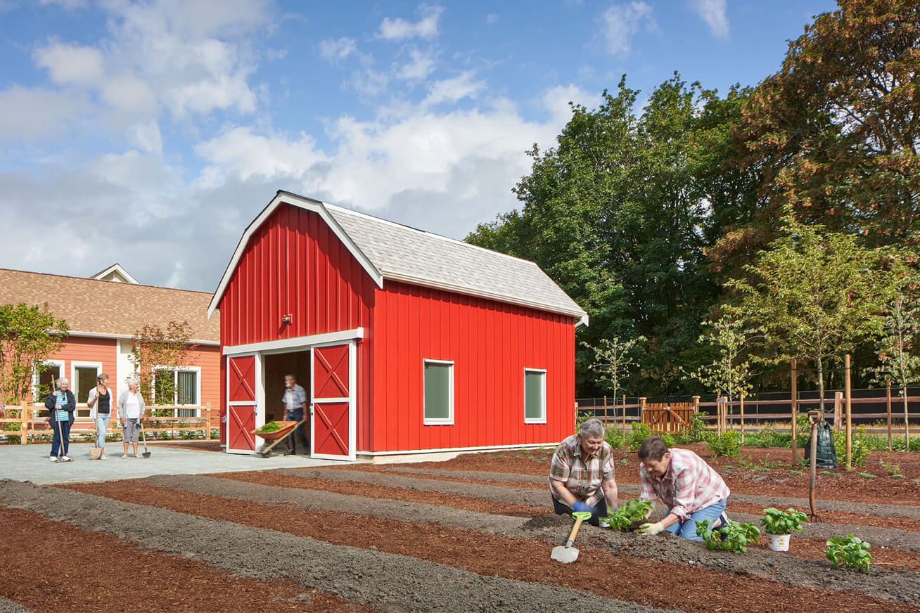 two seniors planting in front of a large red barn