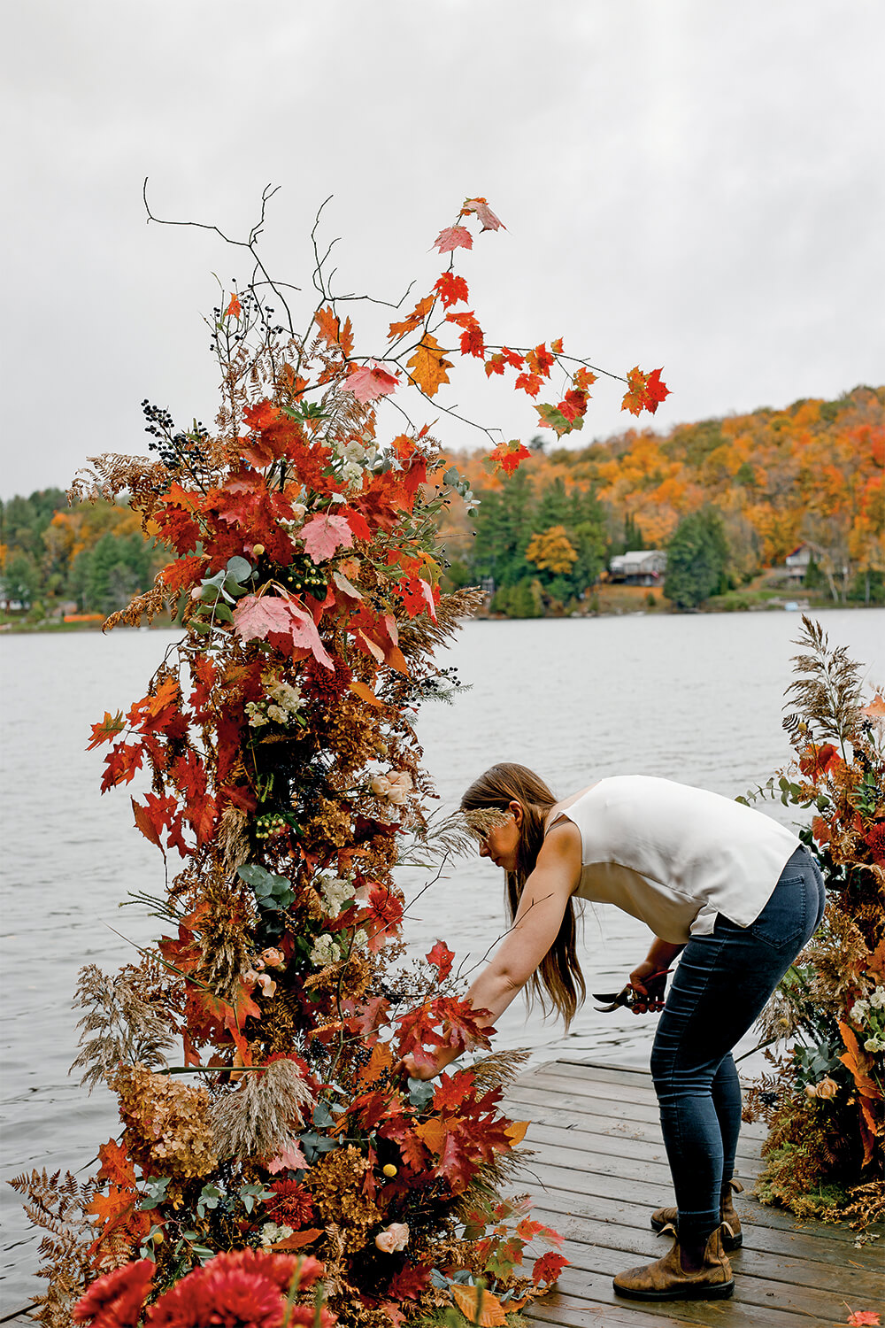 woman on a dock by a lake making a tall planting arrangement