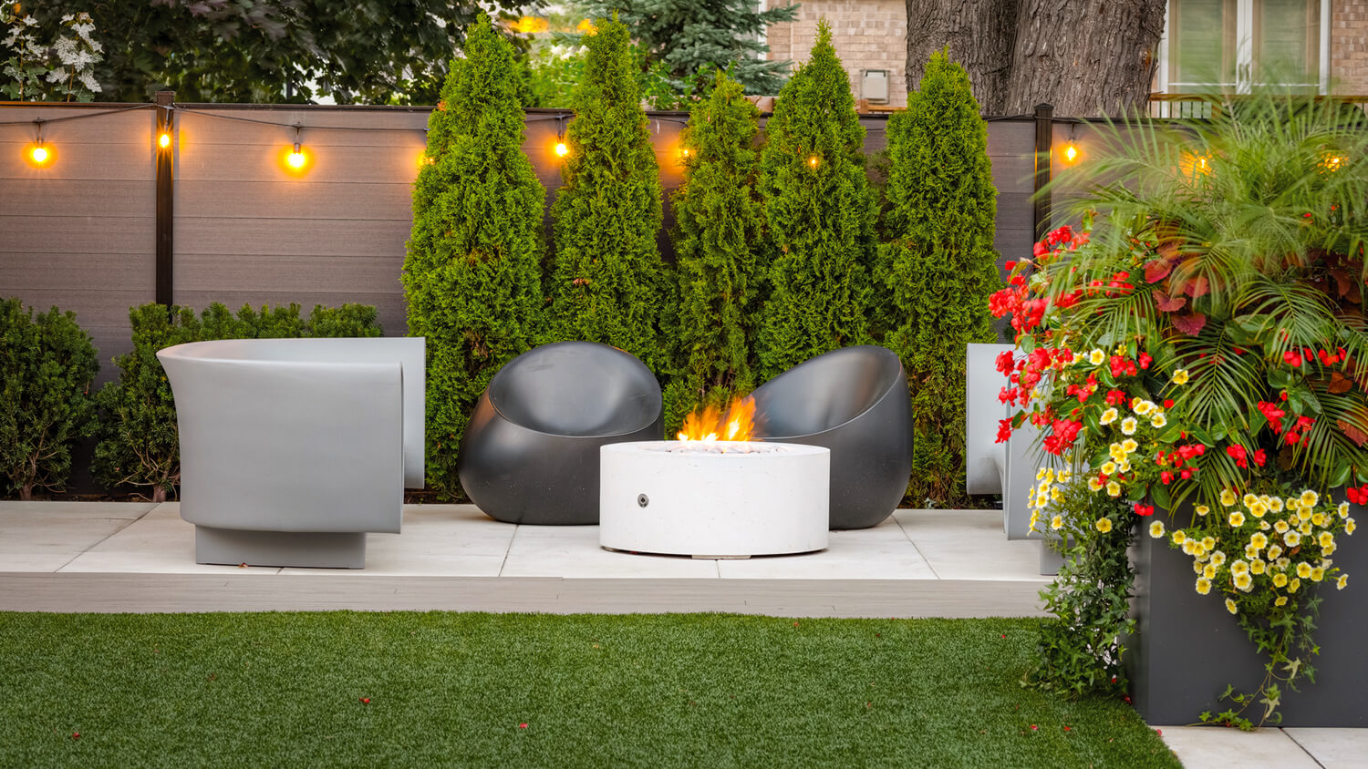 backyard landscape with fence lighting and a fire pit